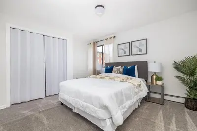 a white bedroom with a large bed with blue pillows at Beautiful 3 bedroom Condo in Hartford! in Hartford