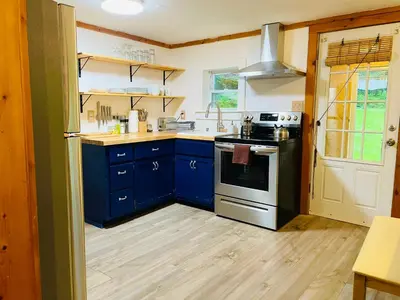 a kitchen with blue cabinets and a stove at Cozy Cottage with Jacuzzi, Sauna, Fire Pit and Reading Nook! in Livingston Manor