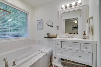 a white bathroom with a tub and a sink and a mirror at 7 Mi to Camelback Mtn Chic Penn Estates Home in East Stroudsburg