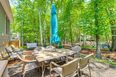 a patio with a table with an umbrella and chairs at 7 Mi to Camelback Mtn Chic Penn Estates Home in East Stroudsburg
