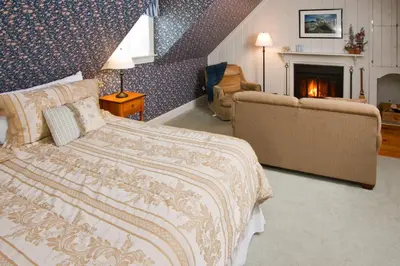 a bedroom with a bed and a couch and a fireplace at Deerfield Valley Inn - Mt Snow BnB Fireplace Rooms and Breakfast in Dover