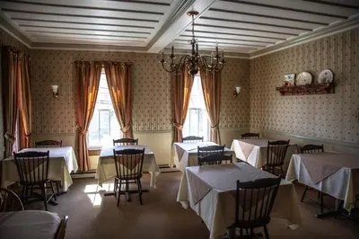 a dining room with tables and chairs and windows at Deerfield Valley Inn - Mt Snow BnB Fireplace Rooms and Breakfast in Dover