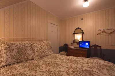 a bedroom with a bed and a laptop on a dresser at Deerfield Valley Inn - Mt Snow BnB Fireplace Rooms and Breakfast in Dover