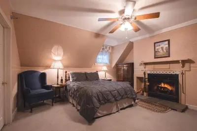 a bedroom with a bed and a chair and a fireplace at Deerfield Valley Inn - Mt Snow BnB Fireplace Rooms and Breakfast in Dover