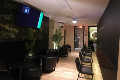 a waiting room with black chairs and a flat screen tv at Nap York Central Park Sleep Station in New York