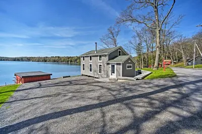 a house sitting on the side of a lake at BBQ Ready Lakeside Milford Home with Paddleboat in Milford