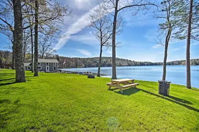 a park with a bench in the grass next to a lake at BBQ Ready Lakeside Milford Home with Paddleboat in Milford