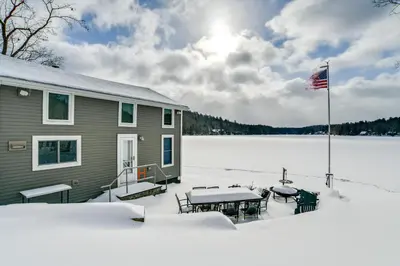 a house in the snow with an american flag at BBQ Ready Lakeside Milford Home with Paddleboat in Milford
