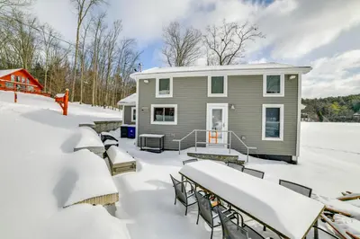 a house covered in snow with tables and chairs at BBQ Ready Lakeside Milford Home with Paddleboat in Milford