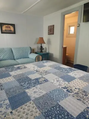 a bedroom with a blue and white quilt on a bed at Serenity Motel in Shaftsbury