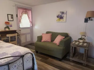 a bedroom with a green couch and a table at Serenity Motel in Shaftsbury