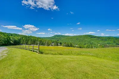 a field with a fence and mountains in the background at Chic Dover Home with Hot Tub 1 Mi to Golf! in West Dover