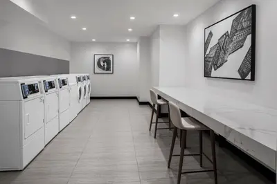 a white laundry room with a long counter and chairs at Four Points by Sheraton Flushing in Queens