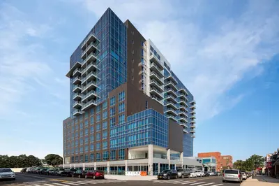 a tall building with blue windows on a street at Four Points by Sheraton Flushing in Queens