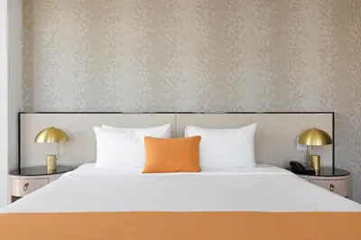 a bedroom with a large bed with an orange pillow at The Parc Hotel in Queens