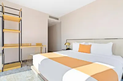 a bedroom with a large white bed with orange pillows at The Parc Hotel in Queens