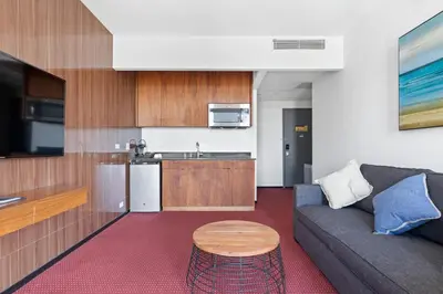 a living room with a couch and a kitchen at The Parc Hotel in Queens