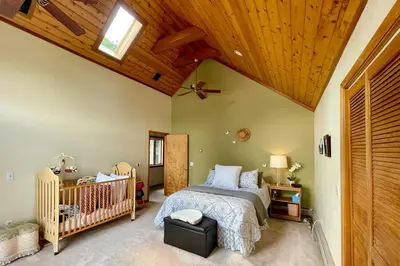 a bedroom with a crib and a wooden ceiling at Lakeside Berkshires Home Near Hiking and Skiing! in Lanesborough