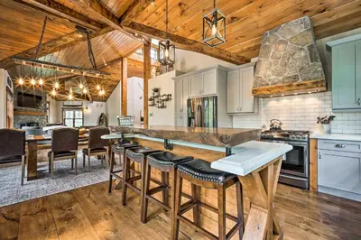 a kitchen with wooden ceilings and a large island with bar stools at Elegant Mtn Chalet with Deck 1 Mi to Mt Snow! in Dover