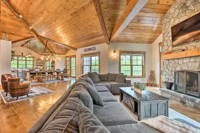 a living room with a large couch and a fireplace at Elegant Mtn Chalet with Deck 1 Mi to Mt Snow! in Dover