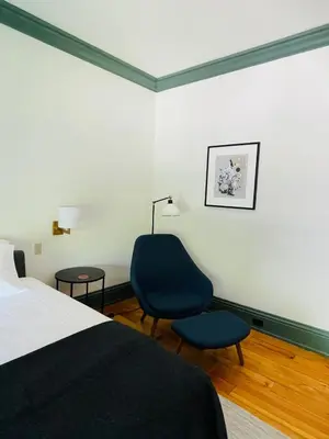 a bedroom with a bed and a chair and a lamp at The Amelia in Hudson