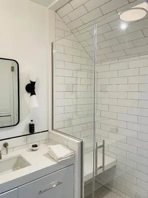 a bathroom with a shower and a sink and a mirror at The Amelia in Hudson