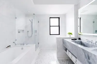 a white bathroom with a tub and a sink at The Wallace Hotel in New York