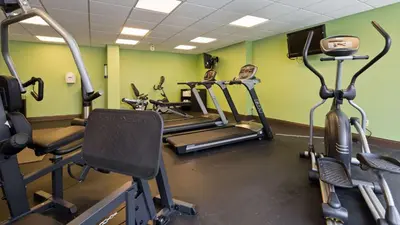 a gym with two tread machines in a room with green walls at Albany Airport Inn in Albany