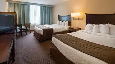a hotel room with two beds and a flat screen tv at Albany Airport Inn in Albany