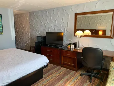 a hotel room with a bed and a desk with a television at Albany Airport Inn in Albany