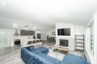 a living room with a blue couch and a kitchen at Modern home with a private Heated pool and jacuzzi in Hamden