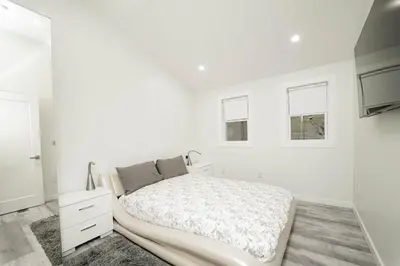 a white bedroom with a large bed and two windows at Modern home with a private Heated pool and jacuzzi in Hamden