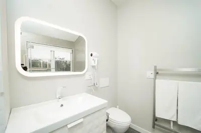 a white bathroom with a sink and a mirror at Modern home with a private Heated pool and jacuzzi in Hamden