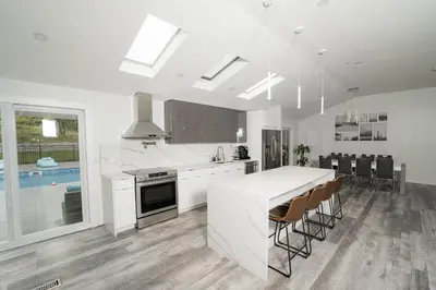 a kitchen with white counters and a kitchen island with chairs at Modern home with a private Heated pool and jacuzzi in Hamden