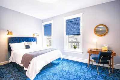 a bedroom with a bed and a table and a mirror at The Hudson Whaler in Hudson