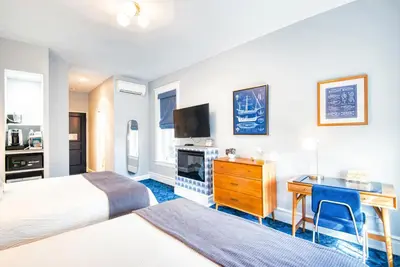 a hotel room with a bed and a desk and a television at The Hudson Whaler in Hudson
