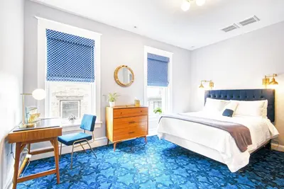 a bedroom with a desk and a bed with blue carpet at The Hudson Whaler in Hudson