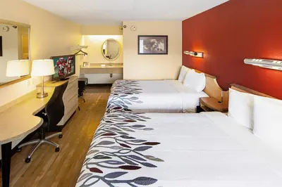 a hotel room with two beds and a desk at Red Roof Inn Utica in Utica