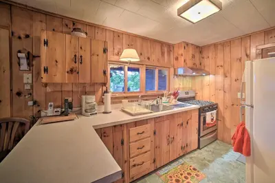 a kitchen with wooden cabinets and a white refrigerator at Riverfront Escape with Dock 19 Mi to Saratoga! in Lake Luzerne