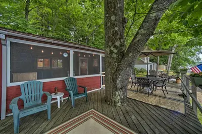 a house with two chairs and a tree on a deck at Riverfront Escape with Dock 19 Mi to Saratoga! in Lake Luzerne