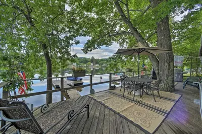 a table and chairs on a deck with a view of a river at Riverfront Escape with Dock 19 Mi to Saratoga! in Lake Luzerne