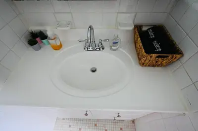 a white sink in a white tiled bathroom at Bright & cozy * 2nd Floor Apartment*. Close to NYC in Bloomfield