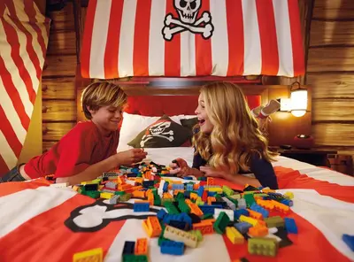 a boy and a girl playing with legos on a bed at LEGOLAND New York Resort in Goshen