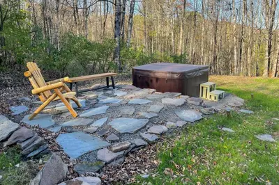 a wooden bench and a wooden barrel in a yard at Modern Catskills Reprieve with Hot Tub and Mtn Views! in Margaretville