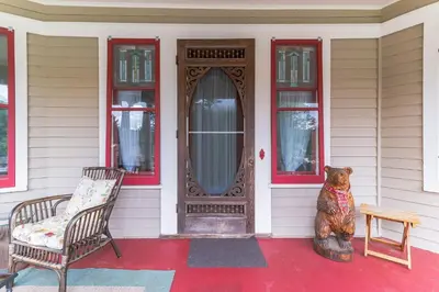 a bear sitting on the front porch of a house at Mountain View Victorian with Convenient Location and Lots of Space tp Play farmhouse in Napanoch