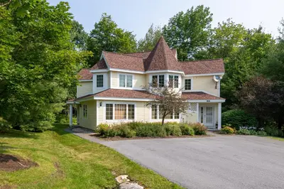 a yellow house with a tiled roof and a driveway at Mount Snow Lodging by Vail Resorts in Dover