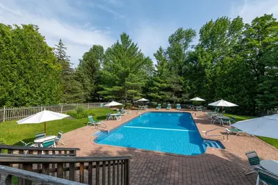 a swimming pool with chairs and umbrellas at Mount Snow Lodging by Vail Resorts in Dover