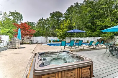 a hot tub on a deck with chairs and umbrellas at Game Room! Poconos Paradise 10 Mi to Ski Slopes in East Stroudsburg