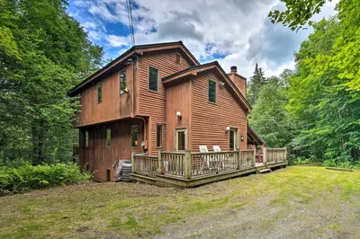 a large wooden house with a deck in the woods at Spacious Dover Home with Sauna Less Than 5 Miles to Ski! in Dover