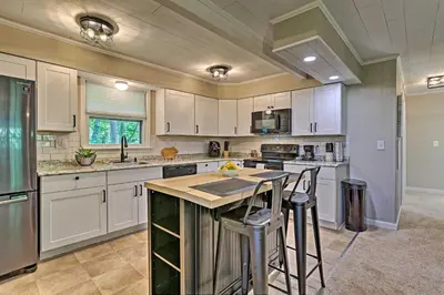 a kitchen with white cabinets and a island with bar stools at Deck and Gas Grill Modern East Stroudsburg Home! in East Stroudsburg